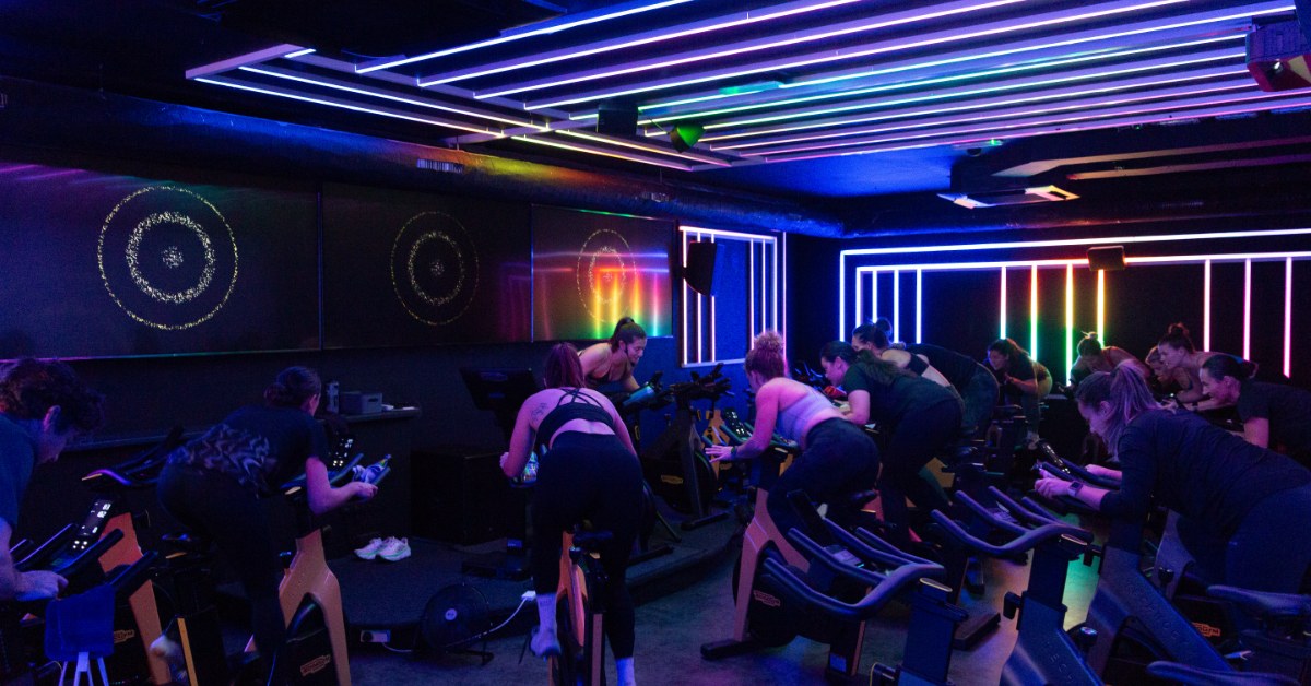 Group indoor cycling class at RINTO Fitness Richmond, with members riding alongside their coach in a bright, motivating studio atmosphere.