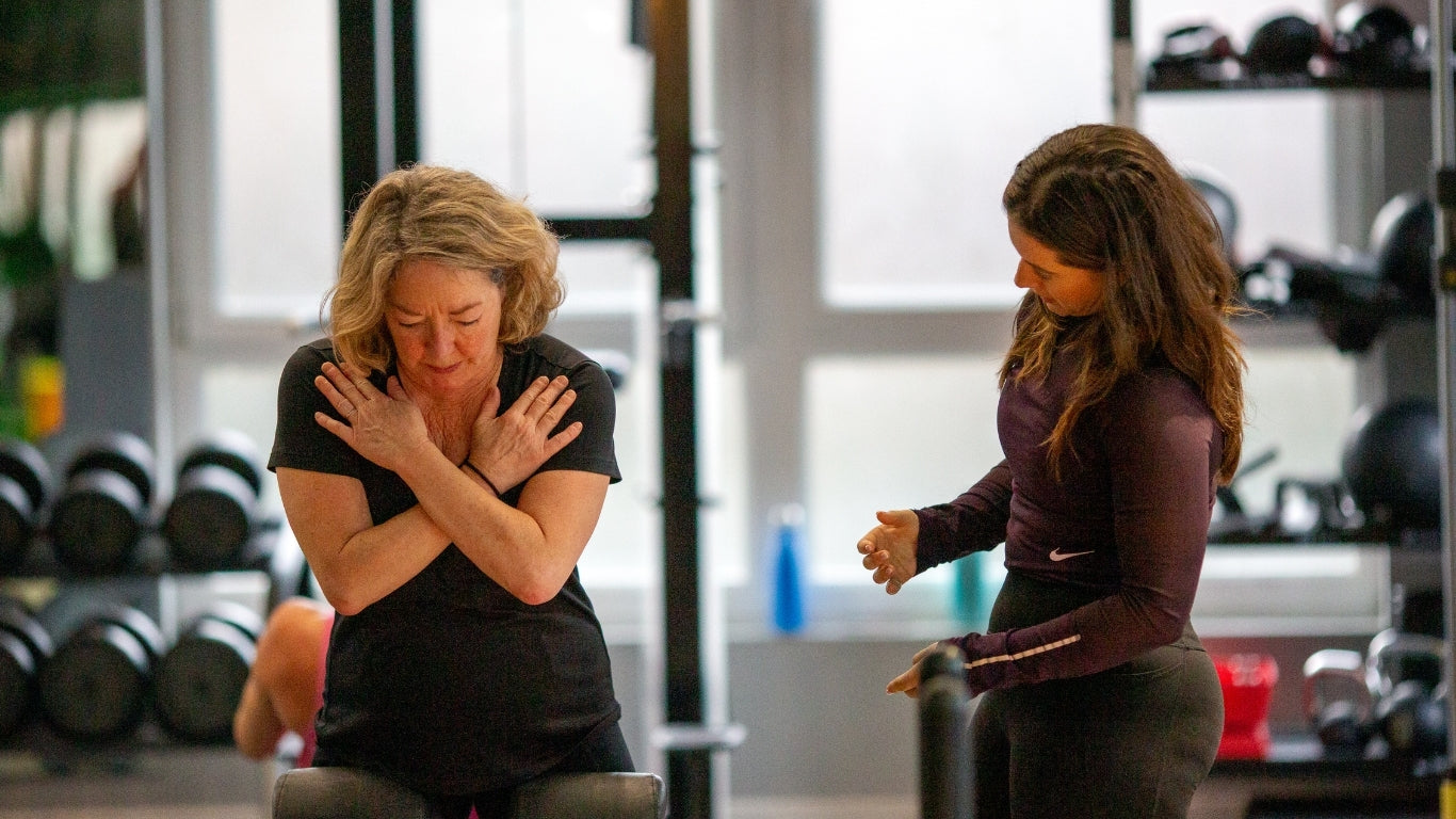 Personal trainer at Rinto Fitness guiding a client through core strengthening exercises in a well-equipped gym setting.